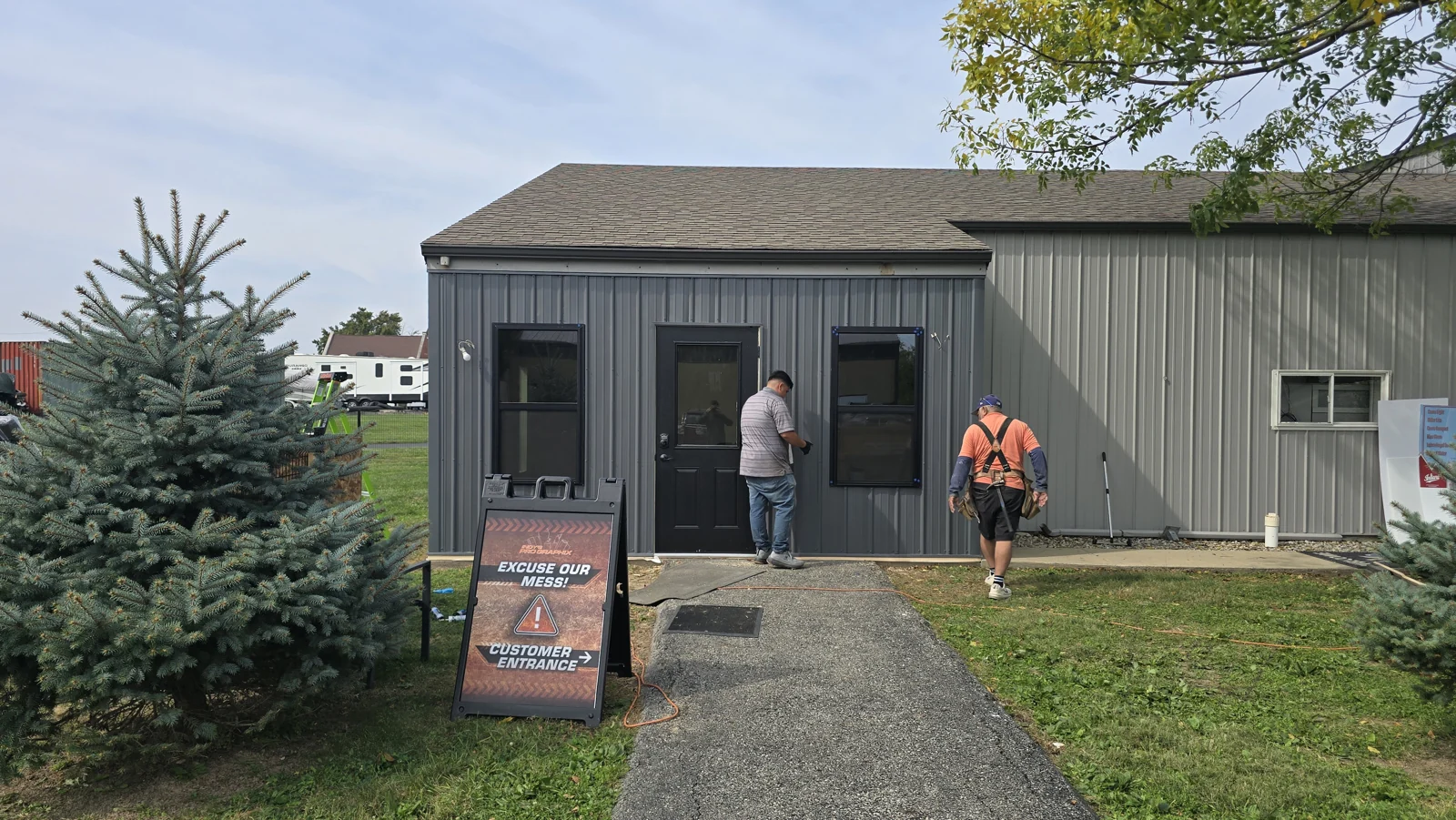 Indy Pro Graphix entrance addition in Whitestown with gray metal siding, two windows and a black entry door